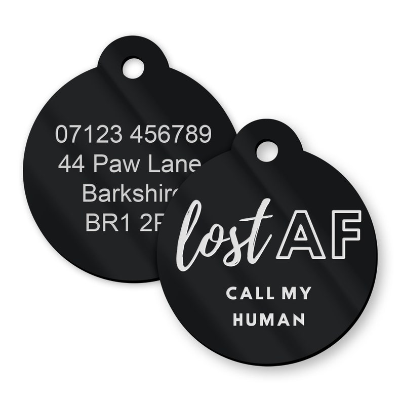 May include: Two black round pet ID tags with white text. The first tag has a phone number, address, and postcode. The second tag says "lost AF" and "CALL MY HUMAN".