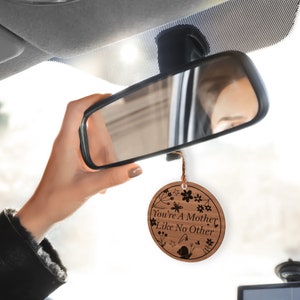 May include: A wooden car air freshener with a floral design and the text "You're a Mother Like No Other".