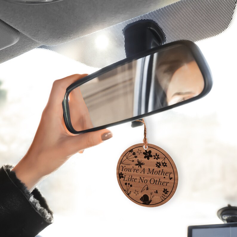 May include: A wooden car air freshener with a floral design and the text "You're a Mother Like No Other".