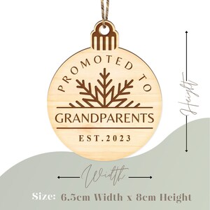 May include: A wooden Christmas ornament with the text "Promoted to Grandparents Est. 2023" and a snowflake design. The ornament is 6.5 cm wide and 8 cm high.