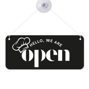 Peut inclure: Panneau rectangulaire noir avec texte blanc et un graphisme de toque de chef. Le panneau indique "Hello, we are open" en gras, police sans-serif. Une ventouse et une ficelle sont attach&eacute;es pour l'accrocher.
