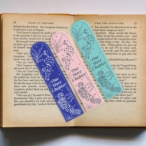 May include: Three colorful bookmarks with a cheetah design and the text "One More Chapter" printed on each. The bookmarks are blue, pink, and teal.