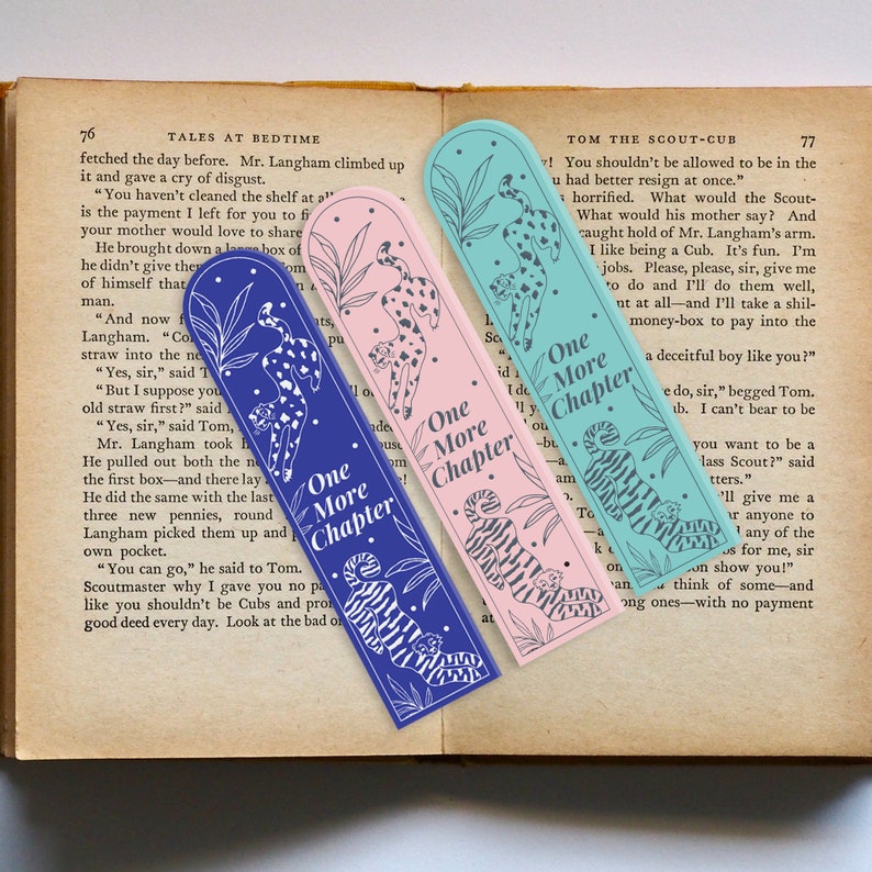 May include: Three colorful bookmarks with a cheetah design and the text "One More Chapter" printed on each. The bookmarks are blue, pink, and teal.