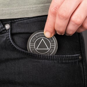 May include: A silver-colored metal token with a black triangle in the center and the text "TO THINK SELF BE TRUE" around the outside. The text "SINCE 2020" is on the left side of the triangle and the text "TO THINK SELF BE TRUE" is on the right side of the triangle.