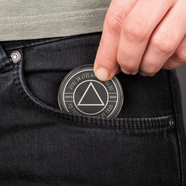 May include: A silver-colored metal token with a black triangle in the center and the text "TO THINK SELF BE TRUE" around the outside. The text "SINCE 2020" is on the left side of the triangle and the text "TO THINK SELF BE TRUE" is on the right side of the triangle.