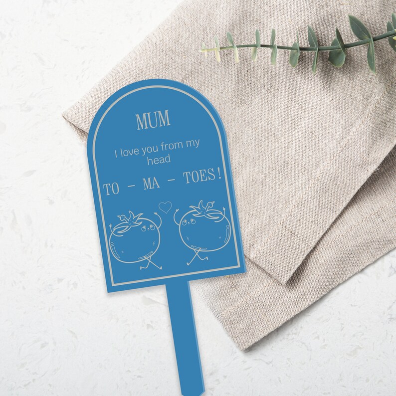 May include: A blue garden stake with a white arch-shaped sign that says "MUM I love you from my head to - MA - TOES!" with two cartoon tomatoes on either side of the text.