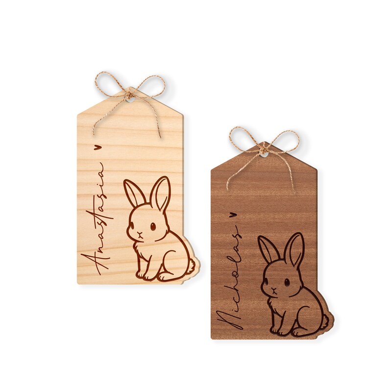 May include: Two wooden gift tags with a bunny rabbit design and personalized names. The tag on the left is light wood with the name Anastasia, and the tag on the right is dark wood with the name Nicholas.