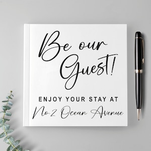 May include: White sign with black text that reads "Be our Guest!" and "Enjoy your stay at No. 2 Ocean Avenue".