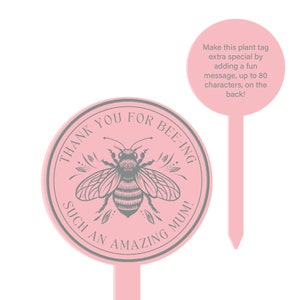 May include: Pink plant tag with a gray bee illustration and the text "THANK YOU FOR BEE-ING SUCH AN AMAZING MUM!"  The tag is round and has a pointed stake on the back.