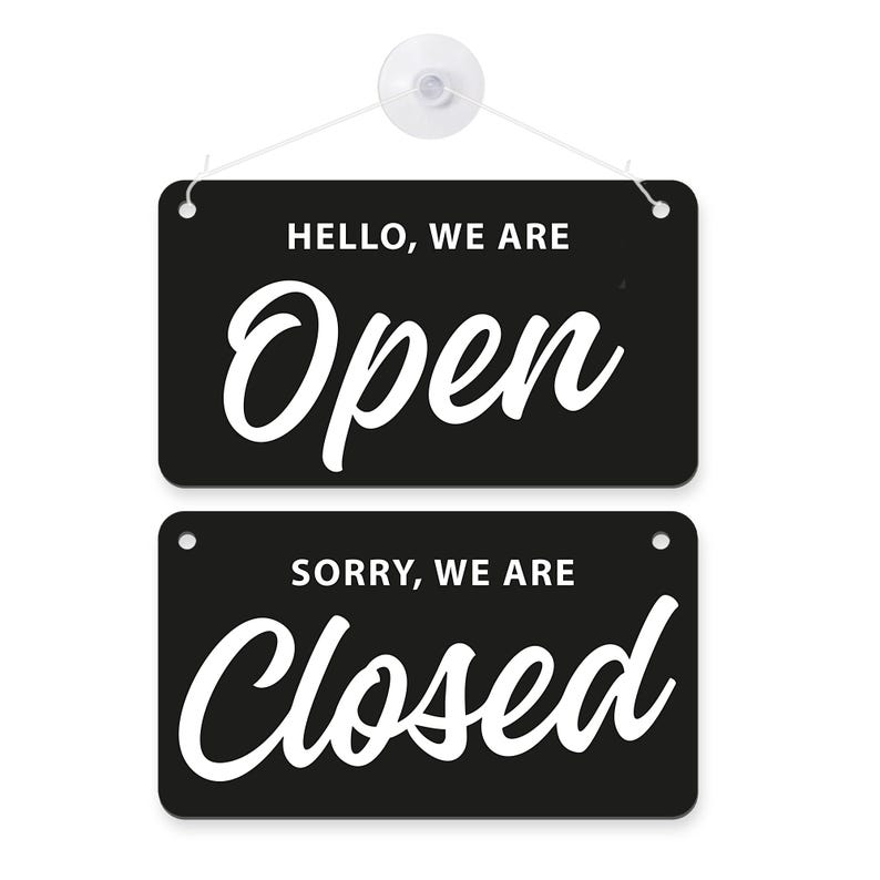 Op de afbeelding: Zwart rechthoekig bord met witte tekst. Boven staat "HELLO, WE ARE Open" in sierlijke letters, en daaronder "SORRY, WE ARE Closed". Ontworpen om openingstijden aan te geven.