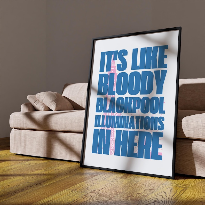 Pu&ograve; includere: Una stampa artistica incorniciata con la scritta "IT'S LIKE BLOODY BLACKPOOL ILLUMINATIONS IN HERE" in blu e rosa. La stampa ha una cornice nera e si trova su uno sfondo bianco. L'opera &egrave; appoggiata a un divano beige.