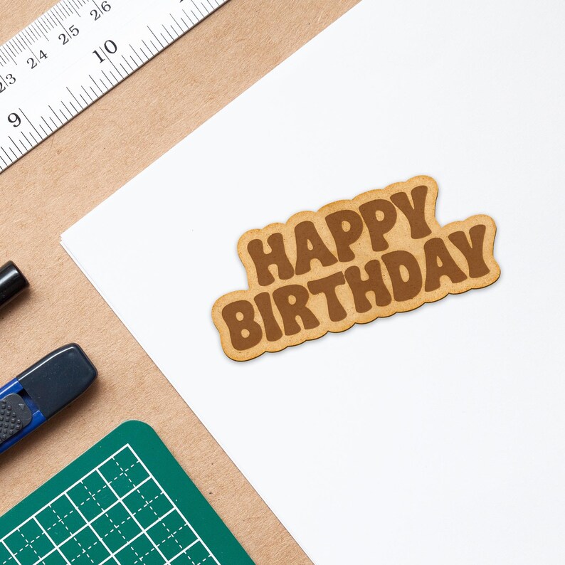 May include: A brown paper card with the words "Happy Birthday" in a brown font.