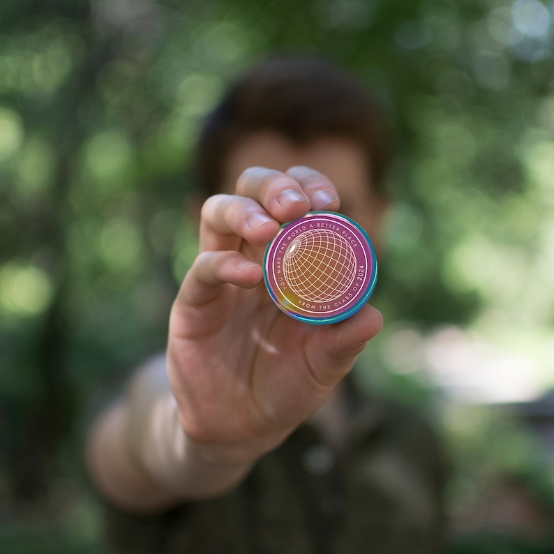 May include: A pink and white round button with the text "Make the world a better place from the class of 2023" and a globe graphic.