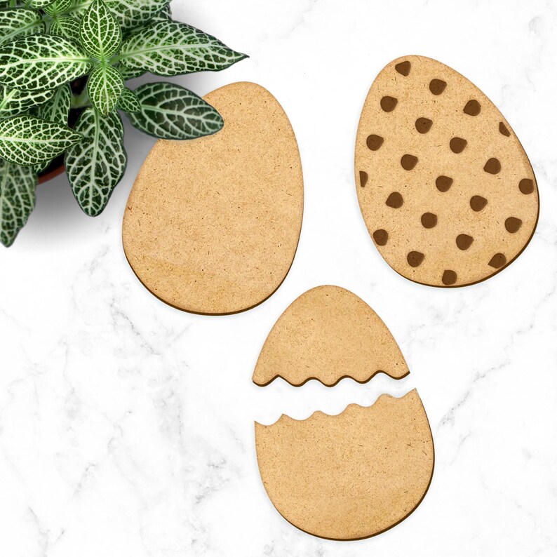 May include: Three wooden Easter egg shapes, one plain, one with brown polka dots, and one with a broken edge.