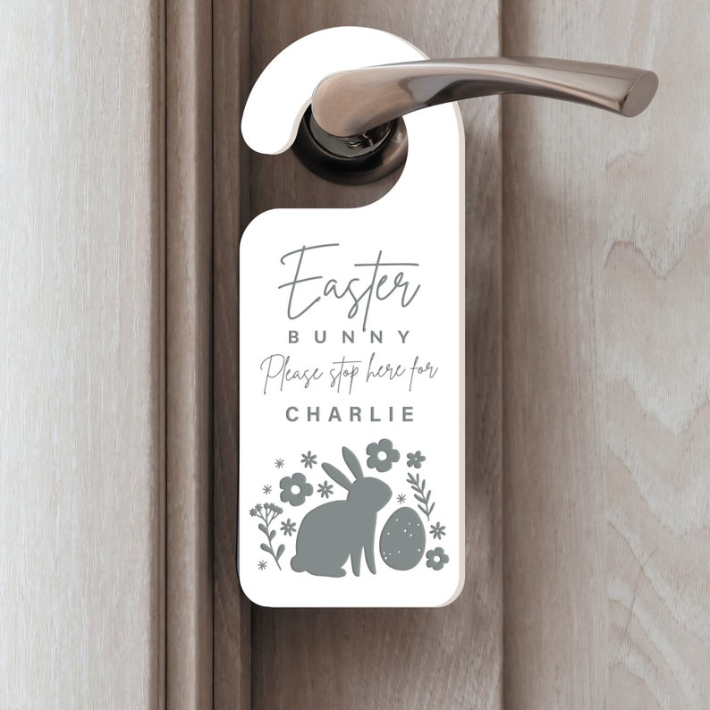 May include: White door hanger with the text "Easter Bunny Please stop here for CHARLIE" and a gray bunny silhouette with an egg and flowers.
