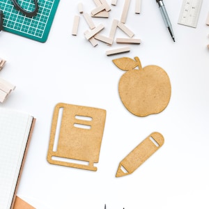 K&ouml;nnte beinhalten: Ein Satz aus Holzschnitten zum Thema Schule, darunter ein Apfel, ein Buch und ein Bleistift. Die Ausschnitte sind braun und haben einen rustikalen Look.