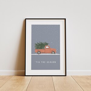 May include: A red pickup truck with a Christmas tree in the bed, driving through a snowy scene. The text 'Tis the Season' is printed below the truck.