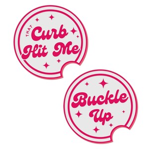 May include: Two white round drink coasters with pink borders and pink text. The first coaster says "That Curb Hit Me" and the second coaster says "Buckle Up".