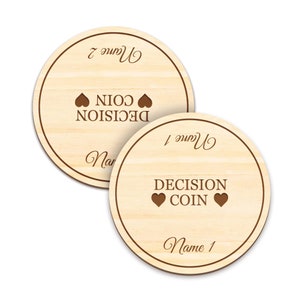 May include: Two wooden decision coins with a light wood grain. Each coin has a dark brown border and the words "DECISION COIN" with heart symbols. One coin reads "Name 1" and the other reads "Name 2".