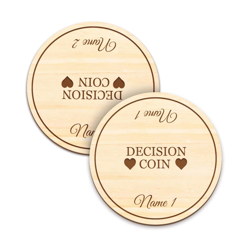 May include: Two wooden decision coins with a light wood grain. Each coin has a dark brown border and the words "DECISION COIN" with heart symbols. One coin reads "Name 1" and the other reads "Name 2".
