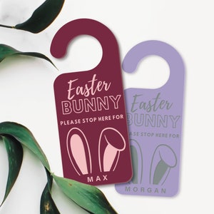 May include: Two purple and burgundy door hangers with bunny ears and the text "Easter Bunny" and "Please stop here for" with a name at the bottom. The door hangers are decorated with bunny ears.