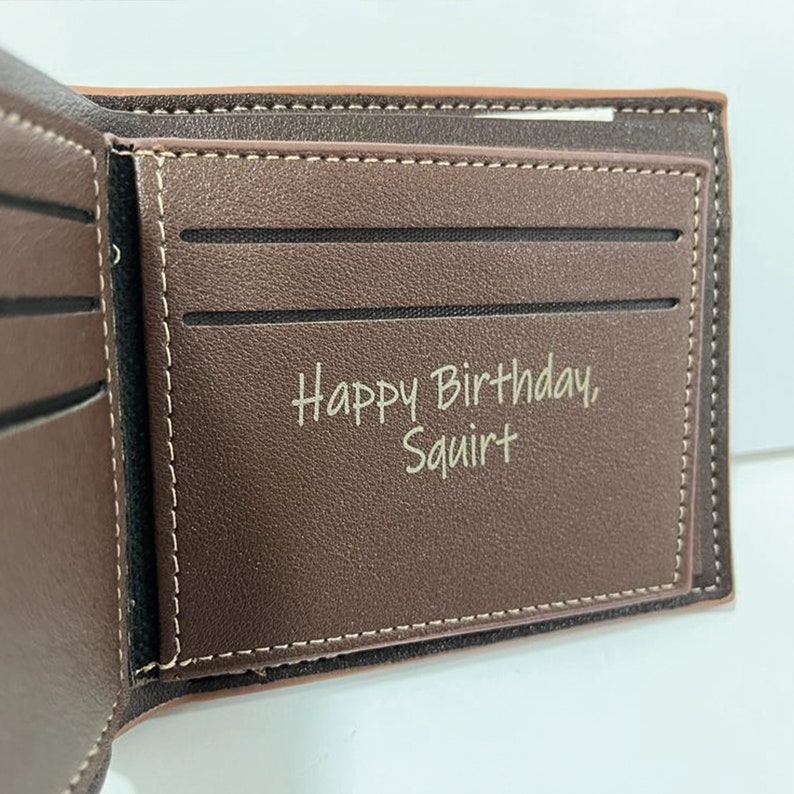 May include: Brown leather wallet with a stitched edge and a personalised inscription that reads "Happy Birthday, Squirt".
