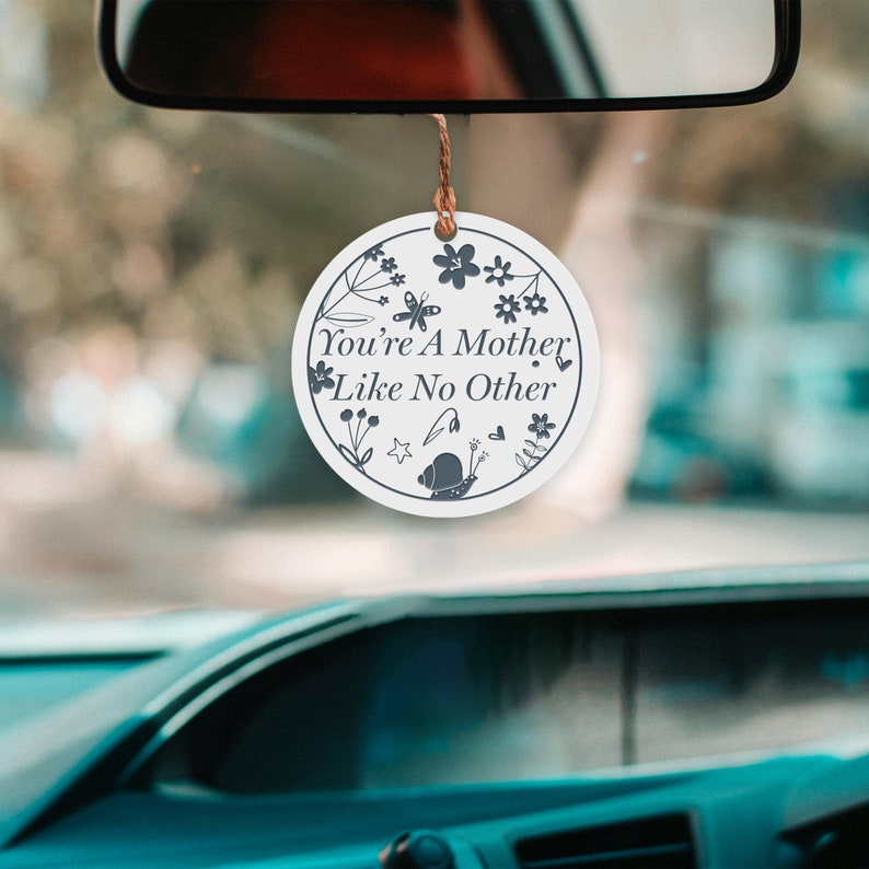 May include: White round car air freshener with a floral design and the text "You're a Mother Like No Other".