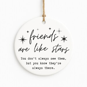 May include: A white ceramic disc ornament with the text "friends are like stars" in black script. The ornament has a jute string for hanging and includes the quote: "You don't always see them, but you know they're always there."