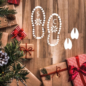 May include: A wooden surface with wrapped gifts, a Christmas tree branch, and white footprints with the letters "S" and "C" on them.