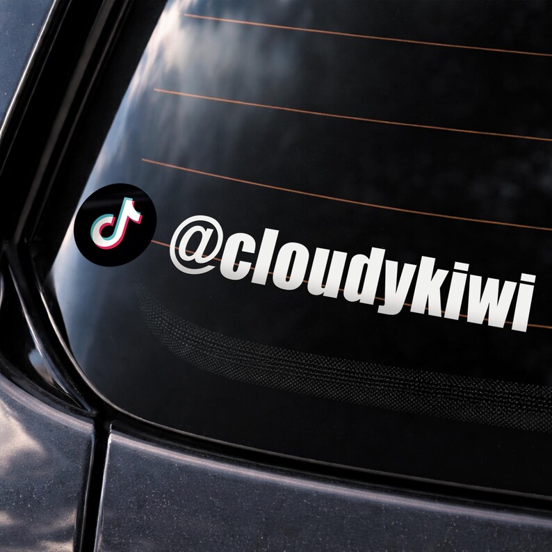May include: A white vinyl sticker with the TikTok logo and the username "@cloudykiwi". The sticker is applied to the rear window of a vehicle. The TikTok logo is a black circle with a white, red, and blue musical note.