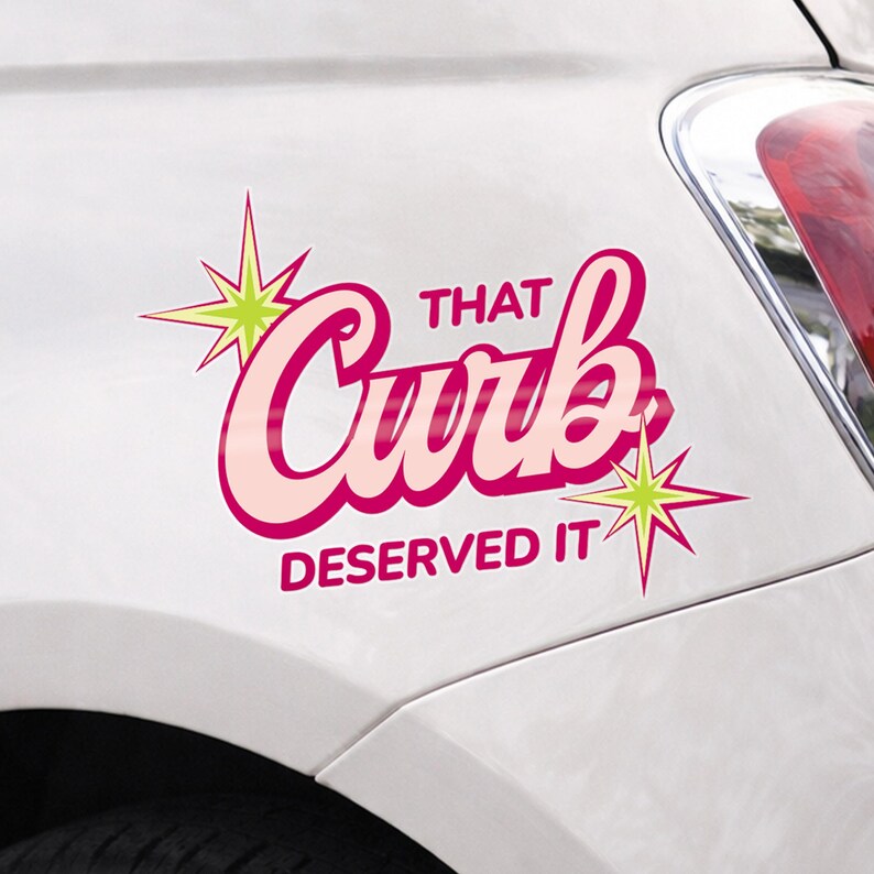 May include: A pink and light pink car decal with the text "THAT Curb DESERVED IT" in a retro font, accented with starburst graphics. The decal is applied to a white car.
