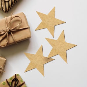 May include: Three brown cardboard stars on a white background. The stars are arranged in a staggered pattern, with the largest star at the top and the smallest star at the bottom.