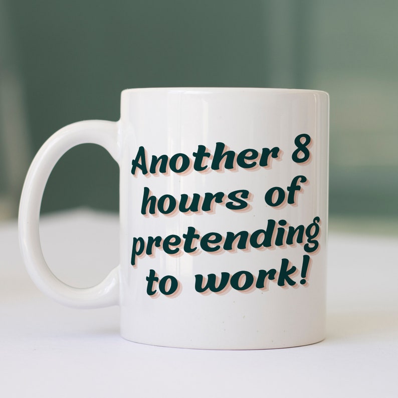 Puede incluir: Taza de cer&aacute;mica blanca con un dise&ntilde;o en negro y naranja. El texto en la taza dice "Another 8 hours of pretending to work!"