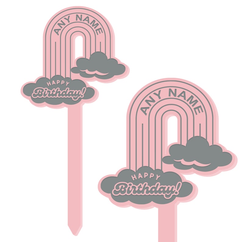 Op de afbeelding: Twee roze en grijze taarttoppers met een regenboog- en wolkendesign. De tekst "Happy Birthday!" en "ANY NAME" staan op de toppers.