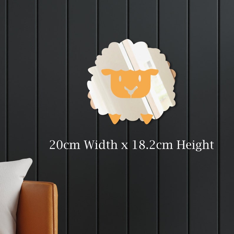 May include: A sheep-shaped mirror with a beige body and orange face and legs. The mirror is 20cm wide and 18.2cm high. The mirror is mounted on a dark grey wall. The text "20cm Width x 18.2cm Height" is below the mirror.