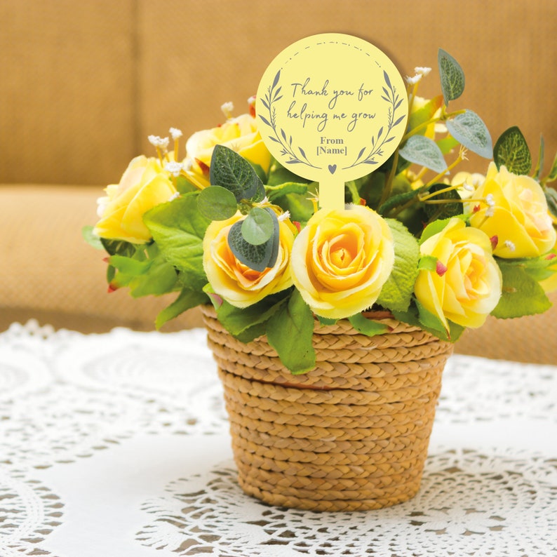May include: A yellow flower arrangement in a woven basket with a yellow circle tag that says "Thank you for helping me grow. From [Name]"