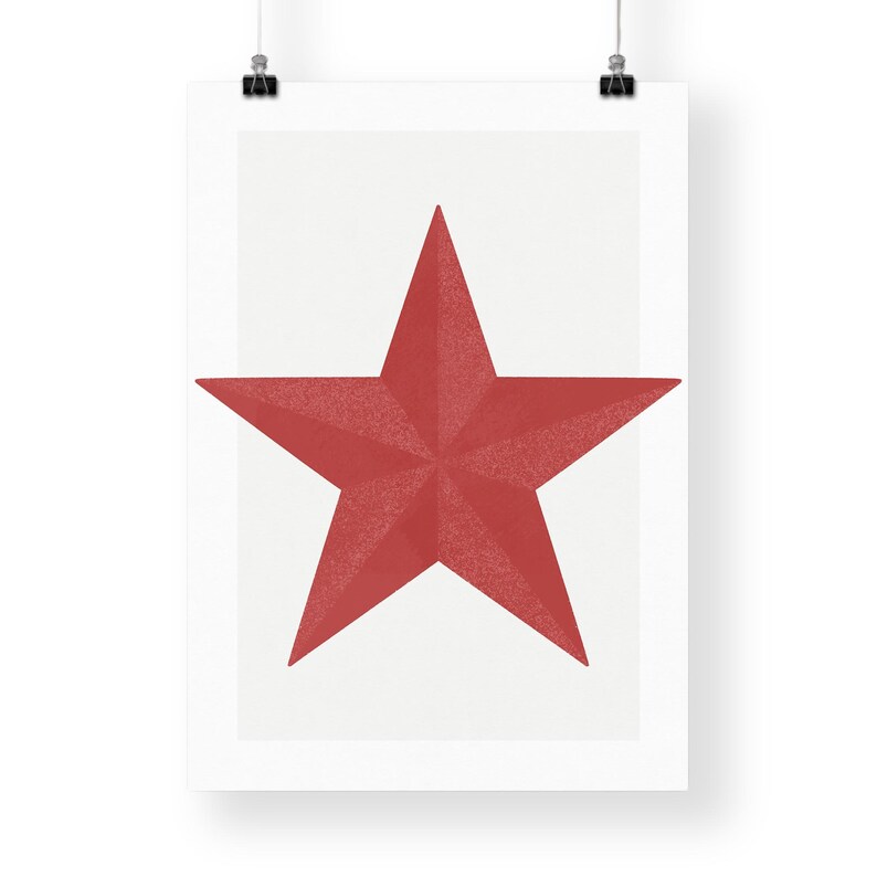 May include: A red five-pointed star on a white background, printed on a poster. The star has a textured appearance and is centered on the poster. The poster is hanging from two black clips.
