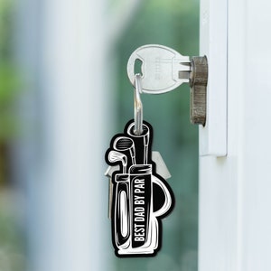 May include: Black and white keychain with a golf bag design and the text "Best Dad By Par".