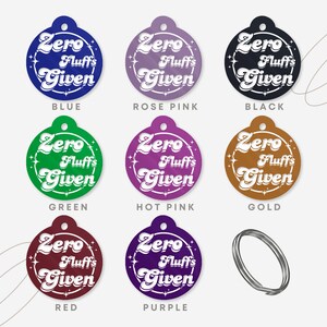 May include: Nine round, colorful, blank pet tags with the text "Zero Fluffs Given" in white. The tags are in the colors blue, rose pink, black, green, hot pink, gold, red, and purple.