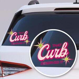 May include: A pink and cream-colored car window decal with the words "That Curb Deserved It" in a retro font. The decal is decorated with starbursts in green and yellow.