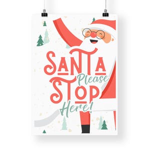 Puede incluir: Un p&oacute;ster blanco con un Pap&aacute; Noel de dibujos animados rojo y blanco con barba blanca y gorro rojo. El texto del p&oacute;ster dice "Santa Please Stop Here!" en letras rojas y verdes.