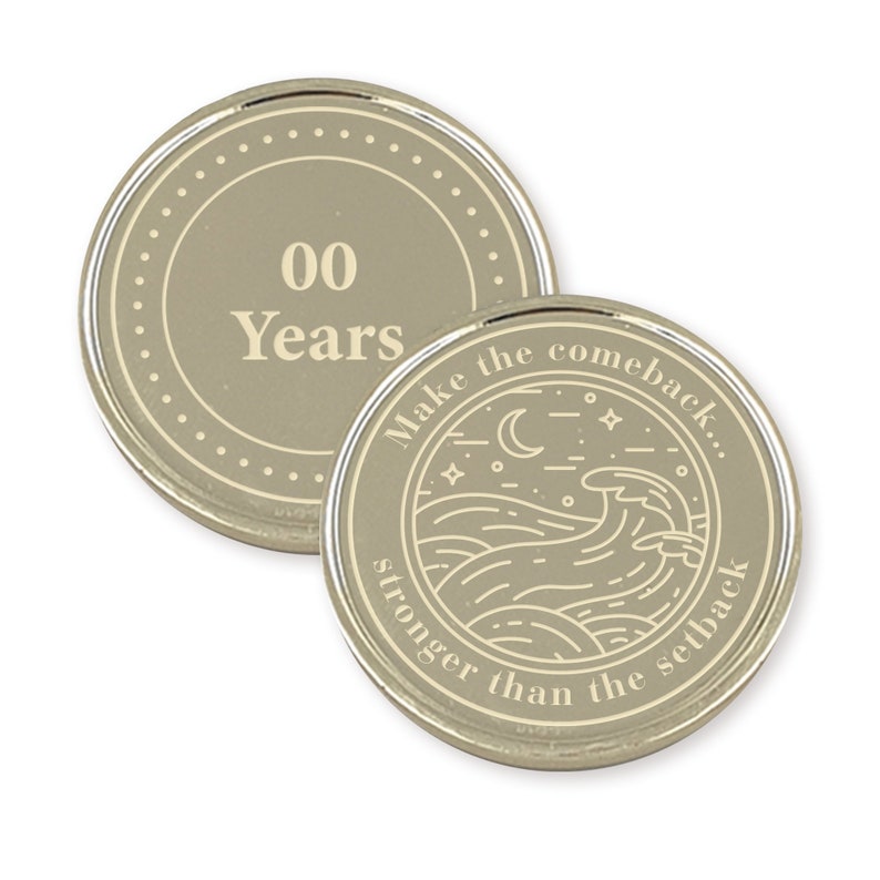 May include: Two silver-colored coins with a beige background. The first coin has the text "00 Years" in a circle. The second coin has a design of a moon, stars, and waves with the text "Make the comeback... stronger than the setback."
