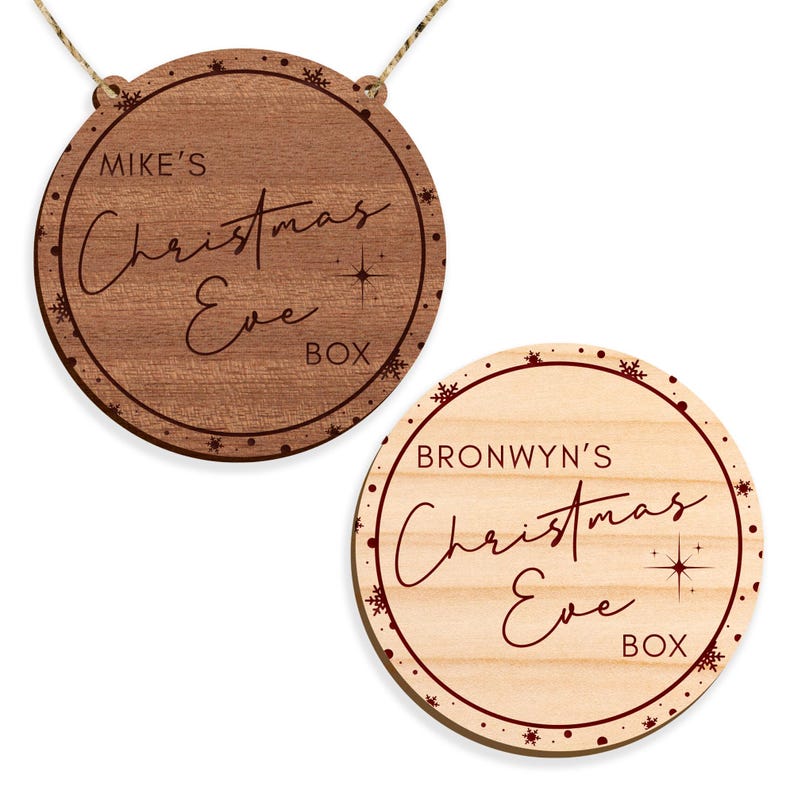 May include: Two round wooden Christmas Eve boxes with red lettering and snowflakes. The top box says "Mike's Christmas Eve Box" and the bottom box says "Bronwyn's Christmas Eve Box".
