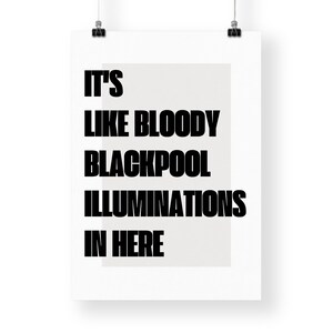 May include: A white poster featuring the phrase "IT'S LIKE BLOODY BLACKPOOL ILLUMINATIONS IN HERE" in bold black text. The text is set against a light grey rectangular backdrop.