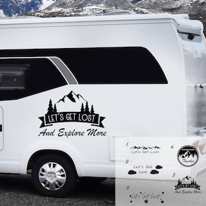 May include: Black and white decal sticker with a mountain range, trees, and the text "Let's Get Lost And Explore More".