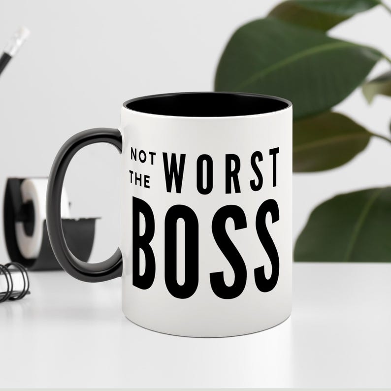 May include: White ceramic mug with a black rim and handle. The mug has black text that reads "Not the Worst Boss".