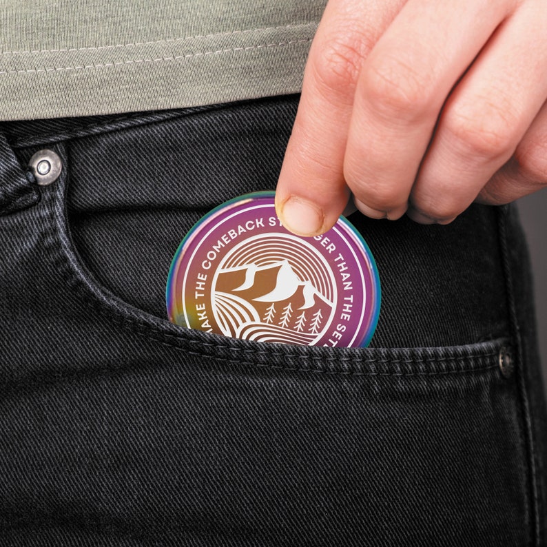 May include: A round, iridescent sticker with the text "Make the Comeback Stronger Than the Setback" in a circle around a graphic of mountains and trees.