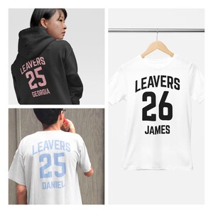 May include: A collage of three items of apparel. A black hoodie with "LEAVERS 25 GEORGIA" in pink lettering. A white t-shirt with "LEAVERS 26 JAMES" in black. A light blue t-shirt with "LEAVERS 25 DANIEL" in blue.
