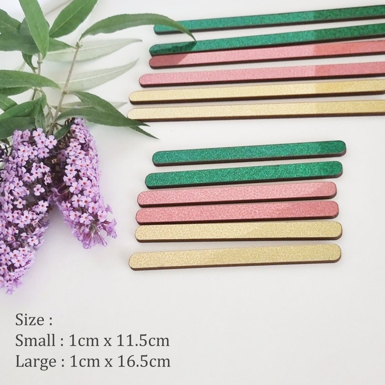 May include: A set of wooden craft sticks in green, pink, and gold glitter. The sticks are 1 cm wide and come in two sizes: small (11.5 cm long) and large (16.5 cm long).