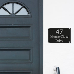 May include: Black house number sign with silver lettering. The sign reads "47 Mouse Close Drive".